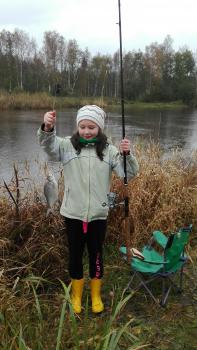 Väike tüdruk poseerib kalaga, mille ta on püüdnud