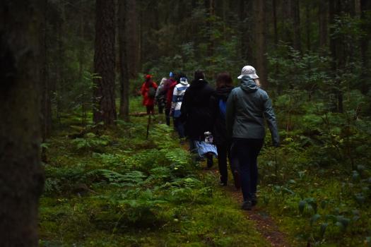 Inimesed kõnnivad üksteise järel hämaras metsas.